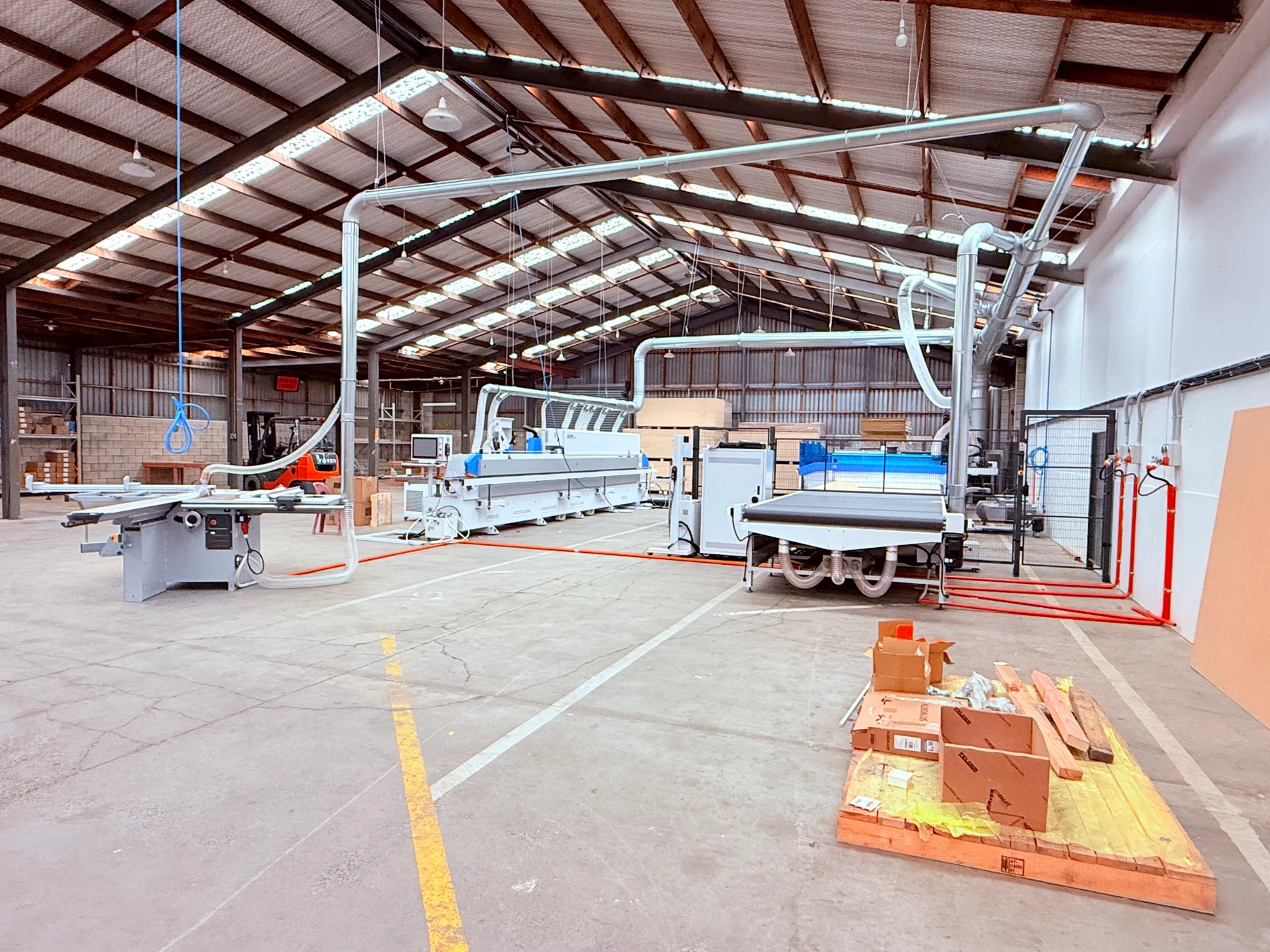 The Reliable Kitchen workshop with cabinetry machinery and overhead extraction ducts.